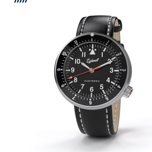 Eylandt The Navigator pilot watch with black dial, matte stainless steel case, knurled bezel, and black leather strap.
